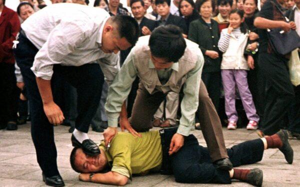 Cảnh sát bắt giữ một học viên Pháp Luân Công tại Quảng trường Thiên An Môn trước sự quan sát của một đám đông xung quanh ở Bắc Kinh vào ngày 01/10/2000. (Ảnh: Chien-min Chung/AP Photo)