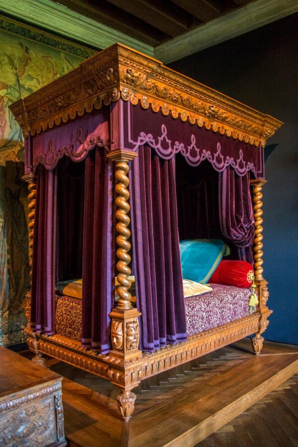 Một điểm nổi bật khác của lâu đài: phòng ngủ của phu nhân Philippe Lesbahy, vợ của ông Gilles Berthelot. Tâm điểm của phòng ngủ là chiếc giường cao, được phục chế theo phong cách Tân Phục Hưng thế kỷ 19. Rèm bằng vải gấm tím, đồ trang trí bằng nhung lụa, đồ thêu, và đồ gỗ tinh mỹ tượng trưng cho sự nguy nga của những chiếc giường thời Phục Hưng cũng như thanh thế của gia chủ. Cuối giường là một rương đựng đồ theo phong cách Tân Phục Hưng. (Ảnh: Steve Allen/Shutterstock)