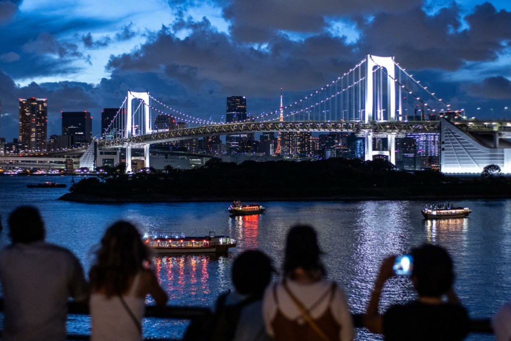Mọi người đến thăm Công viên Hải dương Odaiba, ngắm nhìn Cầu Cầu vồng ở phía sau tại Tokyo, Nhật Bản, hôm 26/08/2023. (Ảnh: Philip Fong/AFP qua Getty Images)