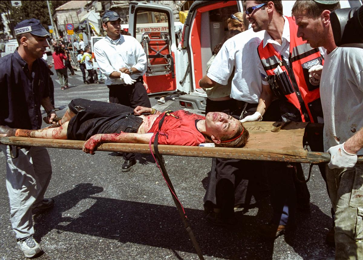 Nhân viên y tế Israel di tản một phụ nữ bị thương khỏi địa điểm một vụ đánh bom tự sát của người Palestine ở Jerusalem vào ngày 09/08/2001. (Ảnh: Getty Images)