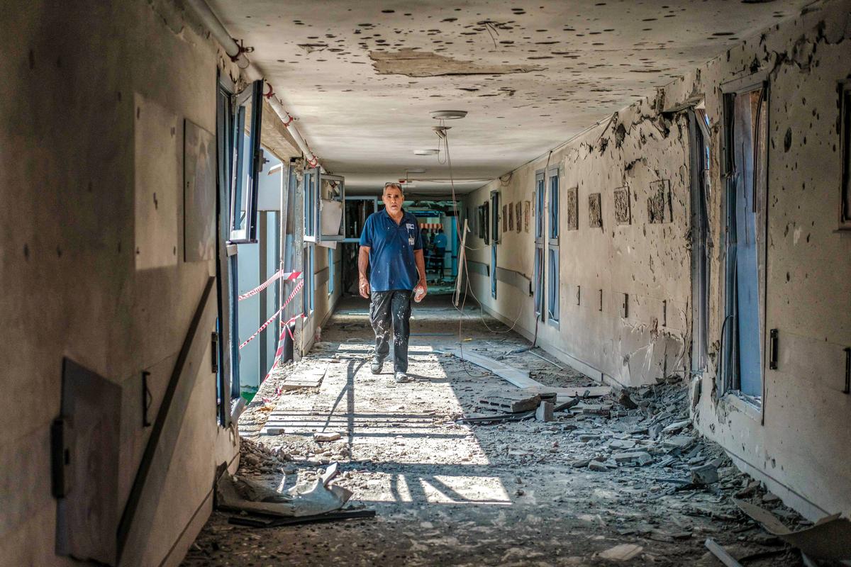 Một nhân viên bệnh viện đi ngang qua khu vực bị phá hủy của Bệnh viện Barzilai sau khi bệnh viện này bị trúng hỏa tiễn, ở Ashkelon, Israel, hôm 11/10/2023. (Ảnh: Tamar Shemesh/Hình ảnh về Trung Đông/AFP qua Getty Images)