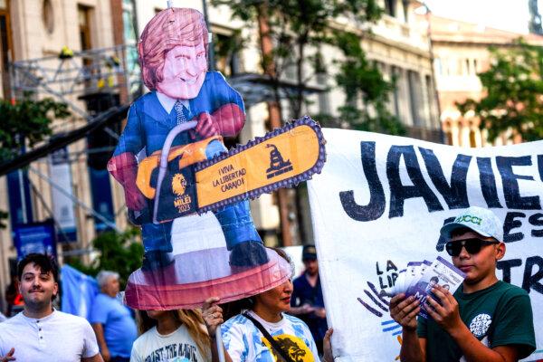 Những người ủng hộ ứng cử viên tổng thống Javier Milei cầm một tấm biển mô tả ông Milei cầm chiếc cưa máy, trước khi cuộc vận động của ông khép lại trước cuộc bầu cử bổ sung ở Cordoba, Argentina, hôm 16/11/2023. (Ảnh: Tomas Cuesta/Getty Images)