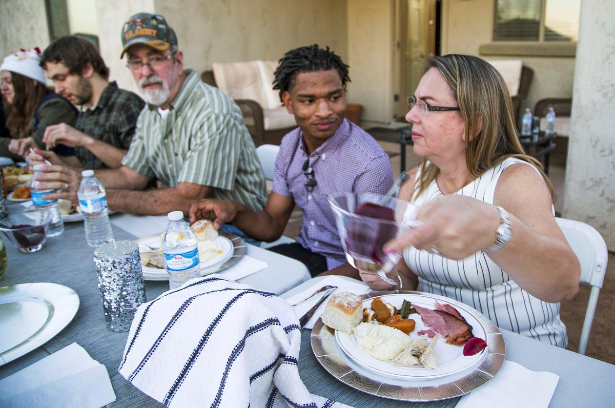 Anh Jamal Hinton (Giữa), bà Wanda Dench (Phải), cùng gia đình và bằng hữu của bà, đang dùng bữa tối Lễ Tạ Ơn tại nhà của bà Dench, ở Mesa, Arizona, vào ngày 24/11/2016. (Ảnh: Tom Tingle/The Arizona Republic qua AP)