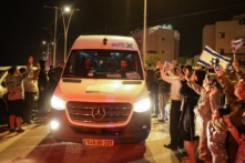 Người dân reo hò khi chiếc xe chở con tin được Hamas thả về phía căn cứ quân sự ở Ofakim, miền nam Israel, hôm 26/11/2023. (Ảnh: Menahem Kahana/AFP qua Getty Images)