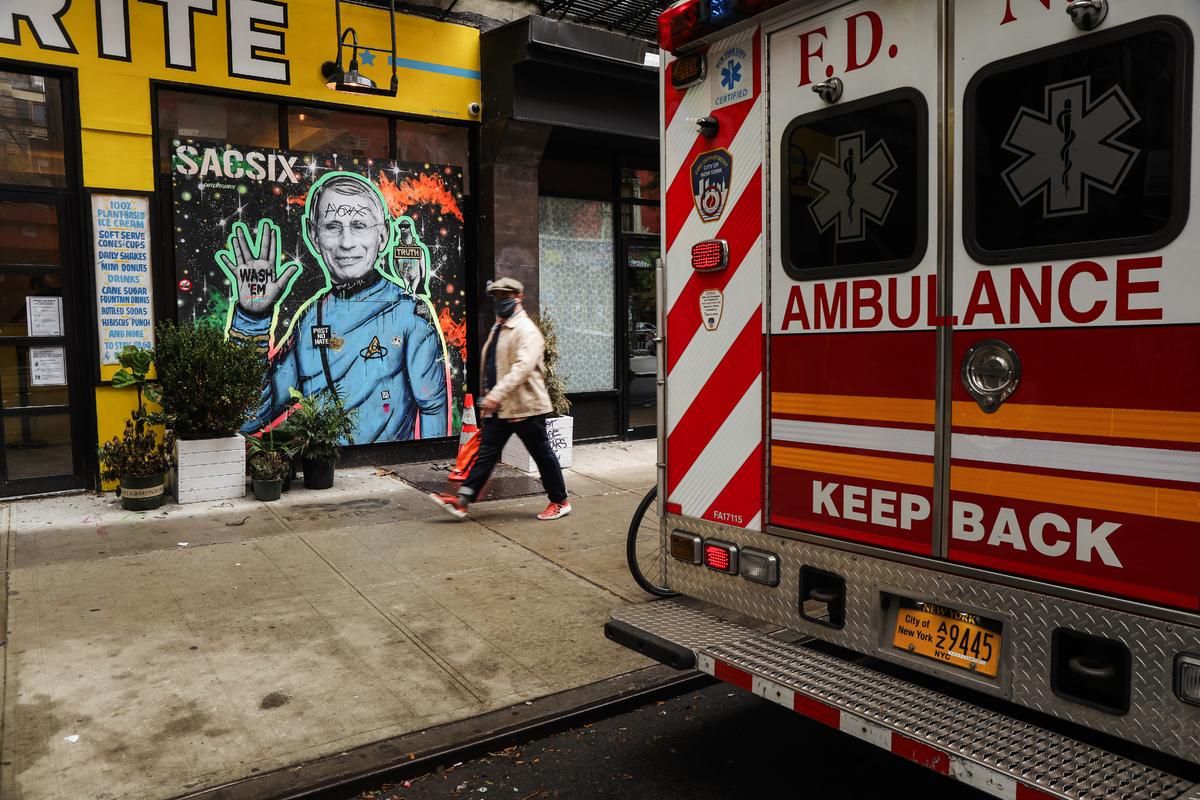 Người dân đi ngang qua bức tranh tường vẽ Tiến sĩ Anthony Fauci ở thành phố New York vào ngày 20/10/2020. Tiến sĩ Fauci gần đây đã bị cựu Tổng thống Donald Trump chỉ trích về phản ứng với COVID-19. (Ảnh: Spencer Platt/Getty Images)