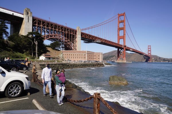 Khách bộ hành tản bộ dọc theo đê chắn sóng, đằng sau là Fort Point và Cầu Cổng Vàng ở San Francisco, hôm 11/10/2020. (Ảnh: Eric Risberg/AP Photo)