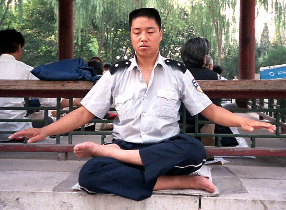 Một nhân viên trật tự công cộng Trung Quốc thực hành thiền định Pháp Luân Công cùng với các đồng tu tại một công viên ở Bắc Kinh, vào ngày 10/06//1999. (Ảnh: Luisetta Mudie/AFP/Getty Images)