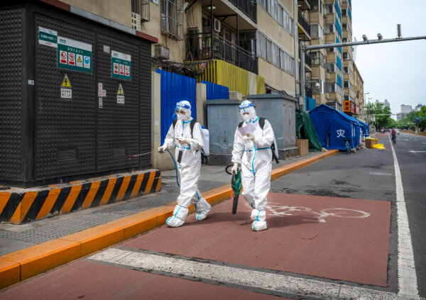 Các nhân viên y tế mặc quần áo bảo hộ khử trùng đi đến khu vực bên ngoài một tòa nhà chung cư đang bị phong tỏa sau khi phát hiện một ca nhiễm COVID-19 ở Bắc Kinh vào ngày 09/05/2022. (Ảnh: Kevin Frayer/Getty Images)