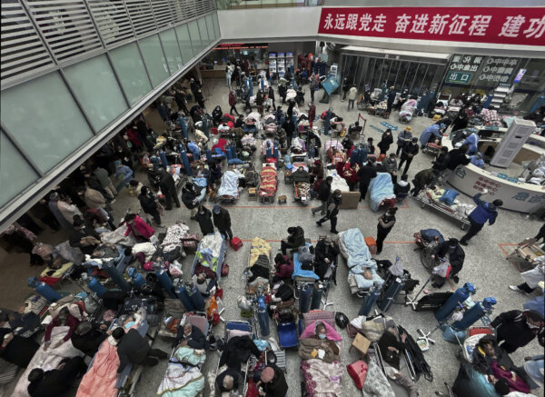 Bệnh nhân được người thân và nhân viên y tế chăm sóc khi họ nằm trên những chiếc giường được đặt ở khu vực thông tầng của một bệnh viện đông đúc ở Thượng Hải, Trung Quốc, vào ngày 13/01/2023. (Ảnh: Kevin Frayer/Getty Images)