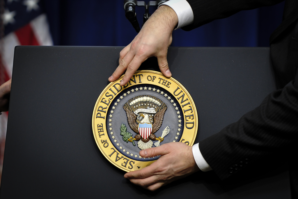 Một nhân viên chỉnh lại huy hiệu của tổng thống trước khi Tổng thống đương thời Barack Obama tổ chức một cuộc họp báo tại Tòa Bạch Ốc vào ngày 22/12/2010. (Ảnh: Jewel Samad/AFP qua Getty Images)