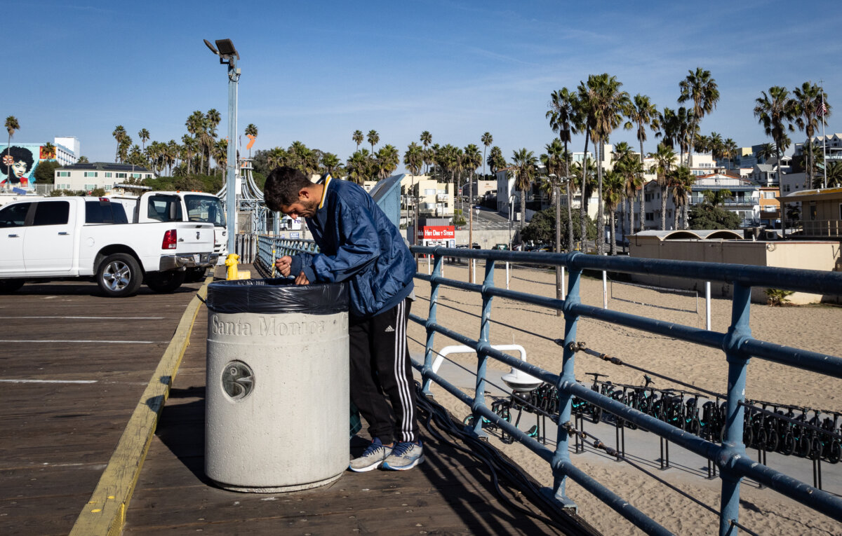 Một người đàn ông vô gia cư bới thùng rác tìm thức ăn ở Santa Monica, California, hôm 08/12/2023. (Ảnh: John Fredricks/The Epoch Times)