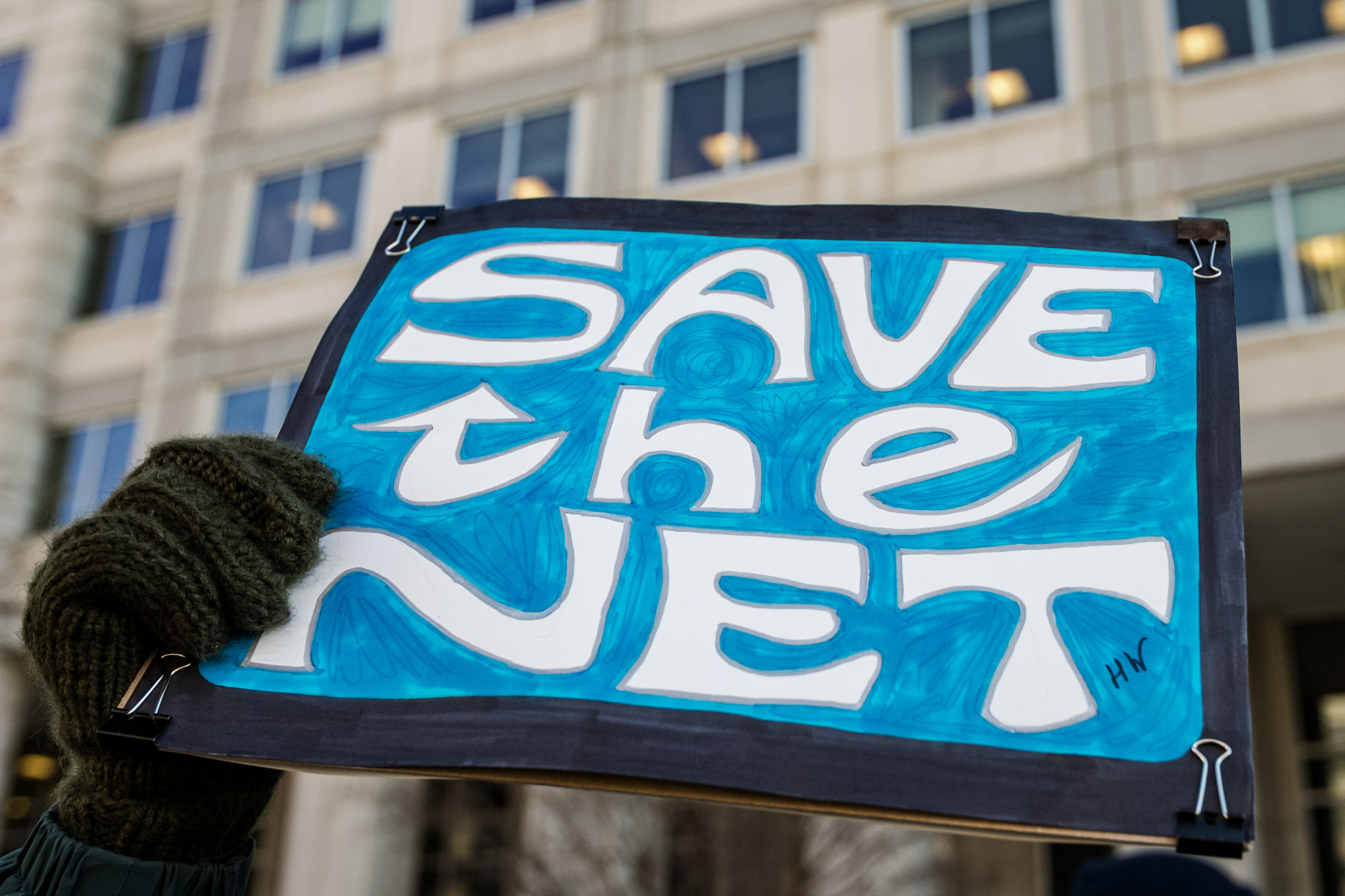 Một người phụ nữ cầm tấm bảng biểu tình ‘Save the Net’ trong cuộc tuần hành phản đối đề xướng bãi bỏ tính trung lập của mạng [xã hội] bên ngoài trụ sở Ủy ban Truyền thông Liên bang ở Hoa Thịnh Đốn vào ngày 13/12/2017. (Ảnh: Alex Edelman/AFP qua Getty Images)