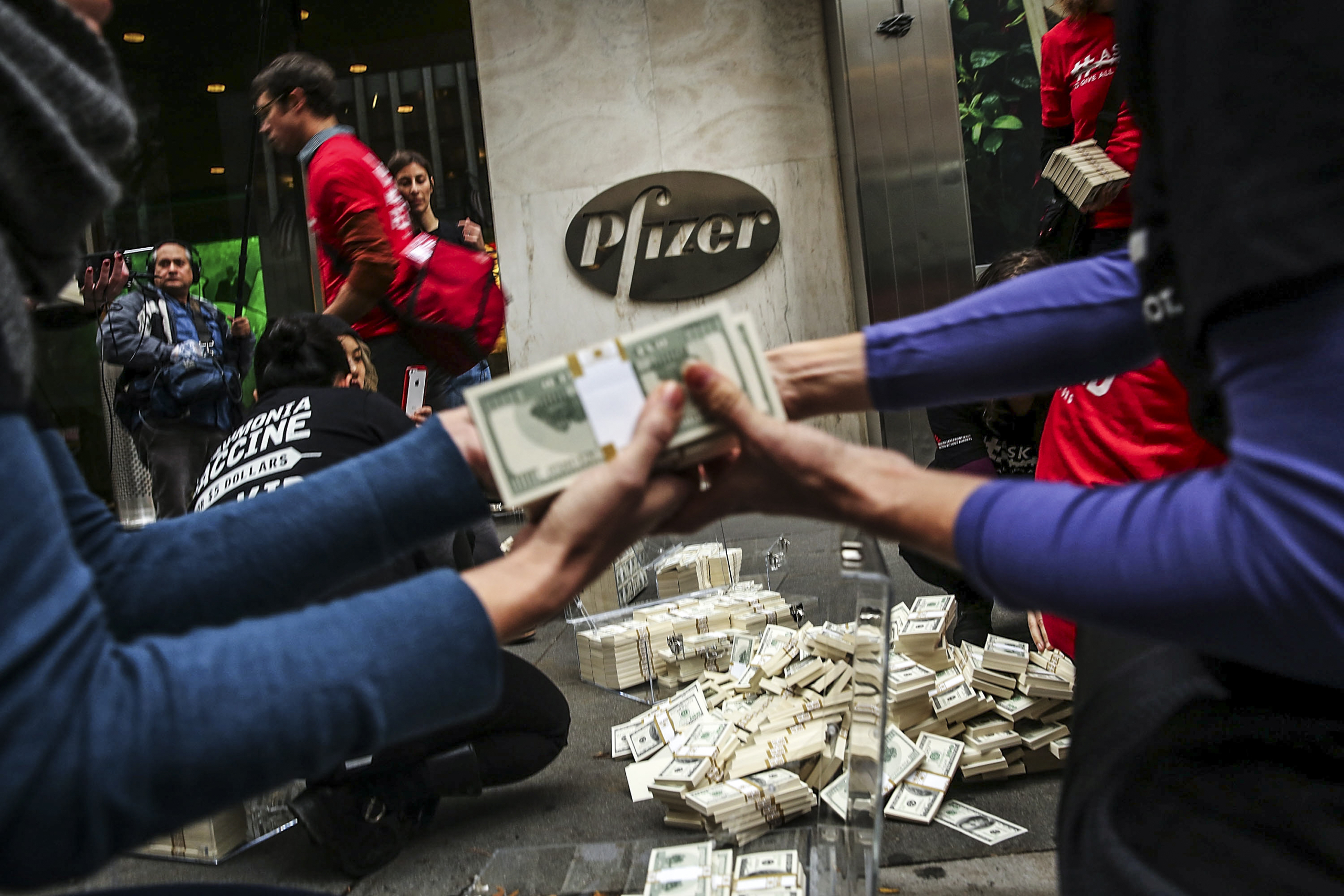 Các tình nguyện viên của Tổ chức Bác sĩ Không Biên giới đổ 17 triệu USD tiền giả bên ngoài trụ sở của Pfizer để phản đối giá vaccine cao, tại New York vào ngày 12/11/2015. (Ảnh: Spencer Platt/Getty Images)