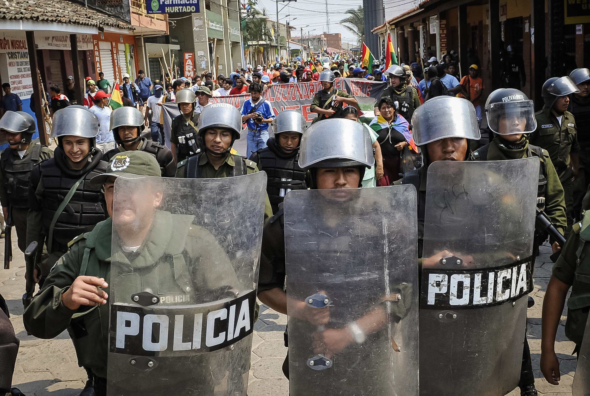 Cảnh sát chống bạo động hộ tống một nhóm người ủng hộ đảng Phong trào Tiến Lên Chủ Nghĩa Xã hội (MAS) của Tổng thống Bolivia Evo Morales, khi họ tiến vào thành phố Montero, phía bắc Santa Cruz, Bolivia, vào ngày 24/09/2008. (Ảnh: Aizer Raldes/AFP qua Getty Images)
