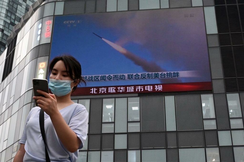 Một người phụ nữ sử dụng điện thoại di động khi đi trước màn hình lớn chiếu một bản tin về các cuộc tập trận quân sự của Trung Quốc xung quanh Đài Loan, tại Bắc Kinh, vào ngày 04/08/2022. (Ảnh: Noel Celis/AFP qua Getty Images)