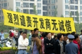 Các chủ nhà giương biểu ngữ có dòng chữ “Hết sức lên án nhà phát triển địa ốc không trung thực” để phản đối tại Khu Chung cư Cannes Thượng Hải, Thượng Hải, Trung Quốc, hôm 14/05/2006. (Ảnh: China Photos/Getty Images)