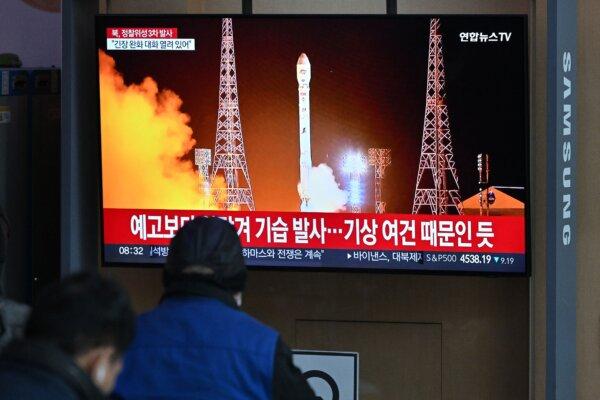 Người dân xem qua màn hình vô tuyến chiếu bản tin có hình ảnh vụ phóng tên lửa mang vệ tinh mới nhất của Bắc Hàn, tại một nhà ga ở Seoul hôm 22/11/2023. (Ảnh: Jung Yeon-Je/AFP qua Getty Images)
