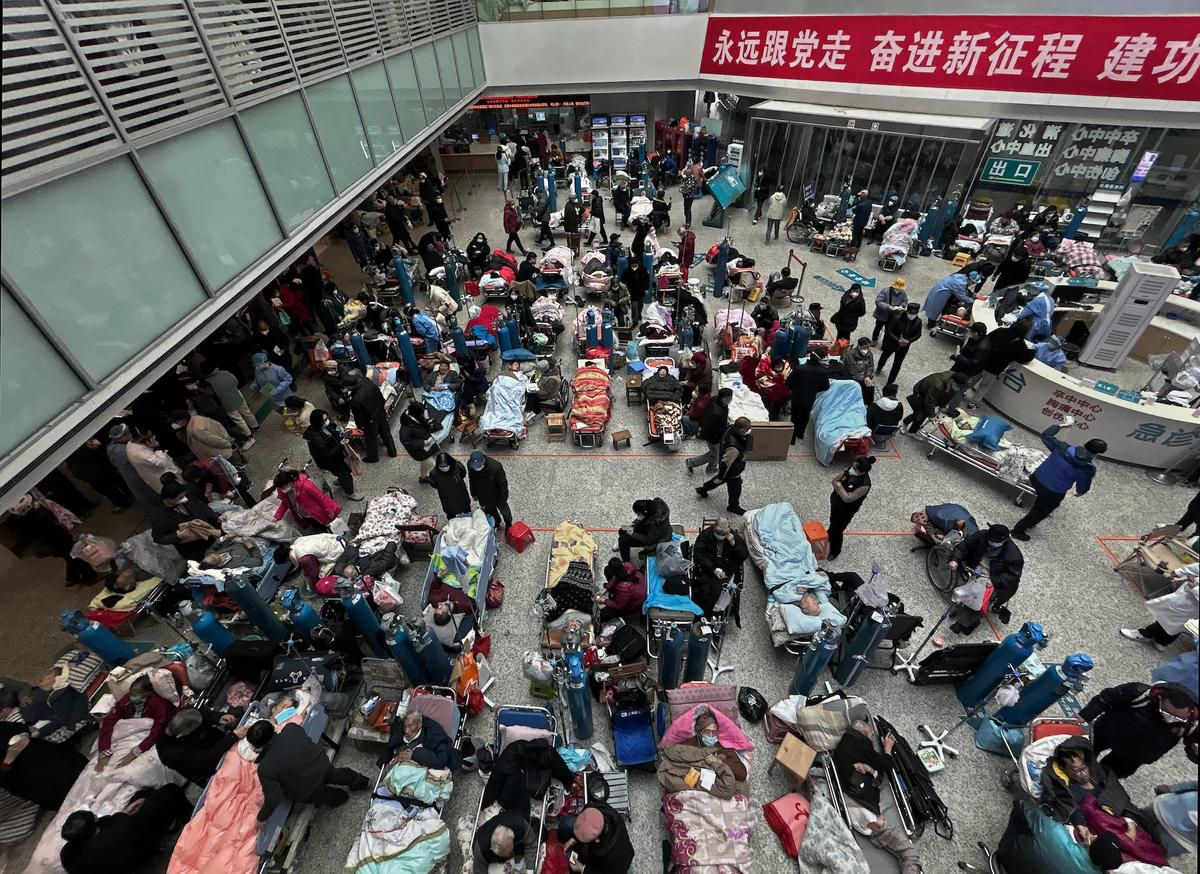 Bệnh nhân được người thân và nhân viên y tế chăm sóc đang nằm trên những chiếc giường được đặt ở khu vực thông tầng của một bệnh viện đông đúc ở Thượng Hải, Trung Quốc, hôm 13/01/2023. (Ảnh: Kevin Frayer/Getty Images)