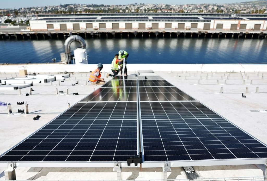 Công nhân lắp đặt các tấm quang năng trên mái nhà sản xuất quang năng rộng 4 mẫu Anh trên đỉnh cơ sở nghiên cứu và phát triển của AltaSea tại Cảng Los Angeles, trong khu phố San Pedro của Los Angeles hôm 21/04/2023. (Ảnh: Mario Tama/Getty Images)