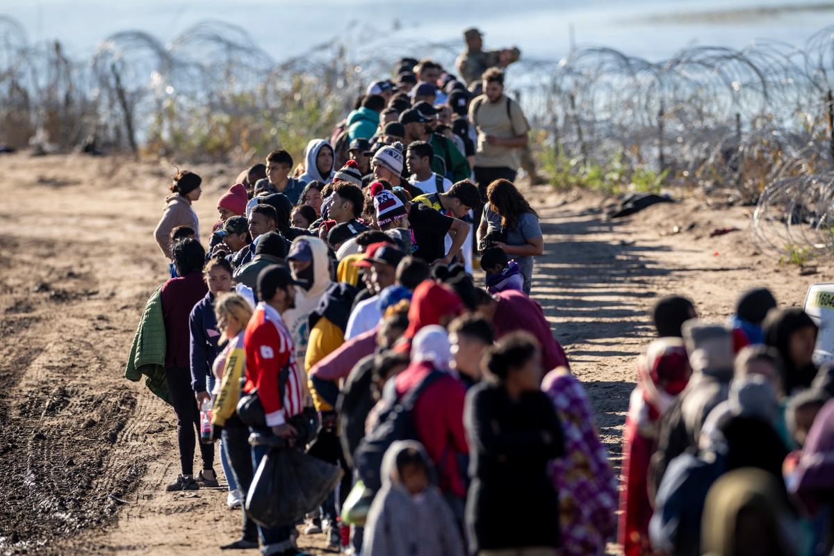 Một nhóm hơn 1,000 người nhập cư bất hợp pháp xếp hàng chờ gần trung tâm giải quyết hiện trường của Đội Biên phòng Hoa Kỳ sau khi vượt sông Rio Grande từ Mexico, ở Eagle Pass, Texas, hôm 18/12/2023. (Ảnh: John Moore/Getty Images)