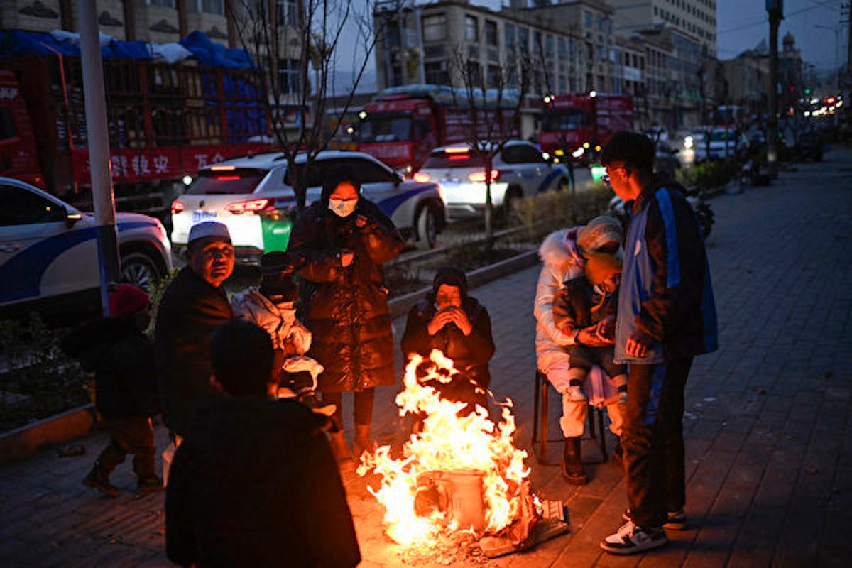 Người dân tụm lại bên đống lửa trên đường phố sau trận động đất ở Đại Hà Gia, huyện Tích Thạch Sơn, tỉnh Cam Túc, ở vùng tây bắc Trung Quốc hôm 19/12/2023. (Ảnh: Pedro Pardo/AFP)