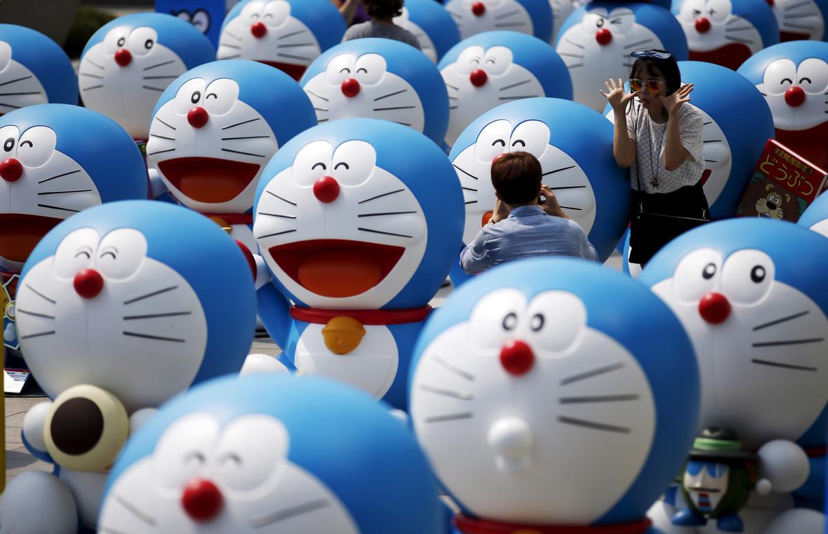 Một người đàn ông chụp ảnh bạn gái của mình tạo dáng bên cạnh nhân vật Doraemon trong một cuộc triển lãm ở Seoul, Nam Hàn, ngày 31/08/2015. (Ảnh: Kim Hong-Ji/Reuters)