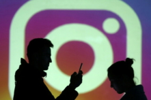 Bóng của người dùng di động đứng cạnh một màn hình chiếu logo của Instagram trong hình minh họa, được chụp ngày 28/03/2018. (Ảnh: Reuters/Dado Ruvic/Illustration)