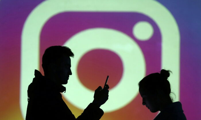 Bóng của người dùng di động đứng cạnh một màn hình chiếu logo của Instagram trong hình minh họa, được chụp ngày 28/03/2018. (Ảnh: Reuters/Dado Ruvic/Illustration)