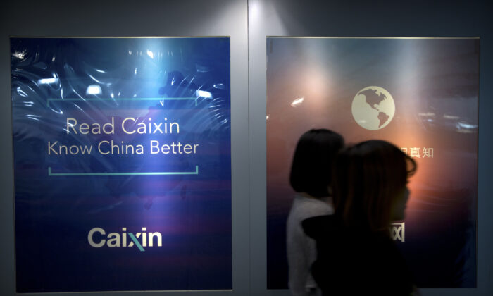 Các nhân viên đi ngang qua một biển quảng cáo tại văn phòng của Tài Tân (Caixin Media) ở Bắc Kinh vào ngày 18/01/2018. (Ảnh: Mark Schiefelbein/AP Photo)
