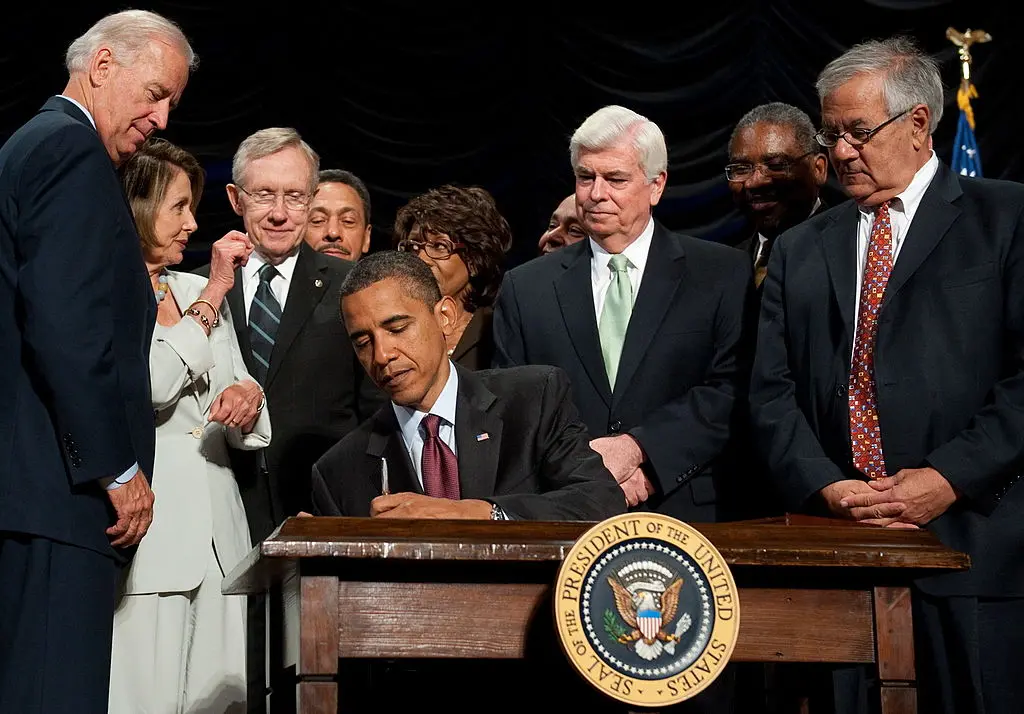 Các thành viên Quốc hội đang chứng kiến Tổng thống đương thời Barack Obama ký Đạo luật Cải tổ Wall Street và Bảo vệ Người tiêu dùng Dodd-Frank trong một bức ảnh tài liệu. Đạo luật này đã cho phép thành lập CFPB hồi năm 2011. 