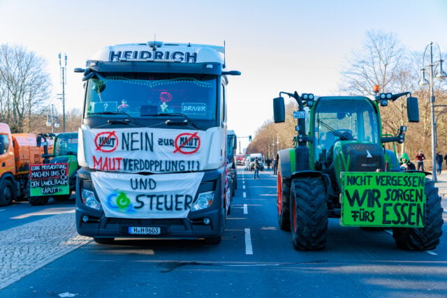 Các tài xế xe tải cùng nông dân phản đối: “Không tăng gấp đôi phí cầu đường và thuế khí thải CO2.” (Ảnh: Zhentong Zhang/Epoch Times)