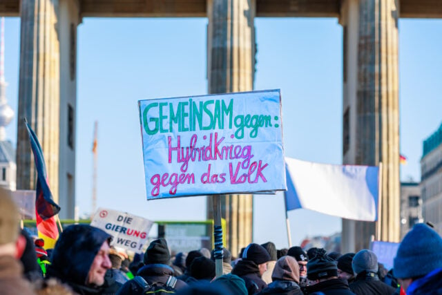 “Cùng nhau phản đối chiến tranh hỗn hợp chống lại người dân” (Gemeinsam gegen Hybrid Krieg gegen das Volk). (Ảnh: Zhentong Zhang/Epoch Times)