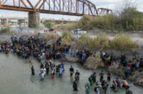 Những người di cư chờ đợi ở Rio Grande để mở hàng rào dây thép gai, để đi vào Hoa Kỳ, ở Eagle Pass, Texas, hôm 25/09/2023. (Ảnh: Andrew Caballero-Reynolds/AFP qua Getty Images)
