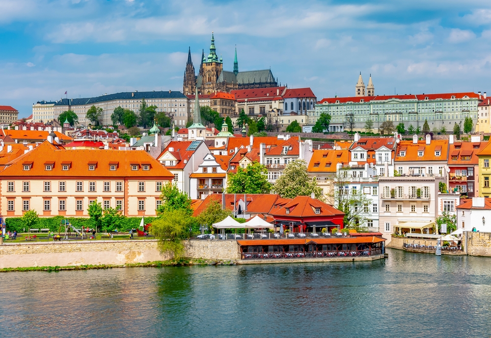 Lâu đài Prague (ở phía xa) nằm trên một ngọn đồi nhìn ra sông Vltava, hướng tầm nhìn ngoạn mục ra thành phố. Còn được gọi là “Prazsky hrad” (tòa lâu đài Prague trong tiếng Czech), khu phức hợp lâu đài này trải dài trên một diện tích rộng lớn, hơn 753.000 feet vuông. Những tháp nhọn và tháp chuông độc đáo của tòa lâu đài nổi bật trên đường chân trời của thành phố. (Ảnh: Mistervlad/Shutterstock)