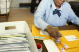 Trong một bức ảnh tư liệu, một nhân viên bưu điện đang dán tem phong bì cho Sở Thuế vụ (IRS). (Ảnh: Monika Graff/Getty Images)