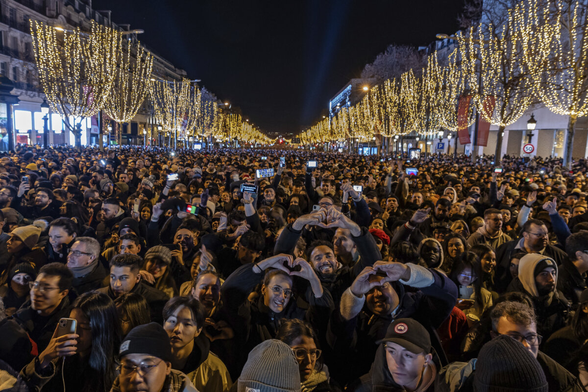 Mọi người xem màn trình diễn ánh sáng được chiếu trên Khải Hoàn Môn khi ăn mừng Năm Mới trên đại lộ Champs Elysees ở Paris, Pháp, hôm 31/12/2023. (Ảnh: Aurelien Morissard/AP Photo)
