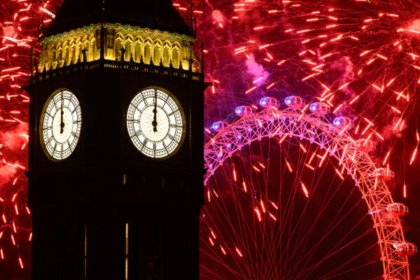 Đồng hồ điểm nửa đêm trên mặt Tháp Nữ hoàng Elizabeth, thường được gọi là Big Ben, khi pháo bông phát ra từ London Eye ở London, Anh, hôm 01/01/2024. (Ảnh: Leon Neal/Getty Images)