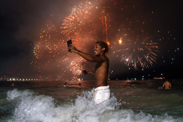 Một người đàn ông giơ điện thoại di động lên khi xem pháo bông mừng Năm Mới truyền thống từ trên mặt nước tại Bãi biển Copacabana ở Rio de Janeiro, Brazil, hôm 01/01/2024. (Ảnh: Tercio Teixeira/AFP qua Getty Images)