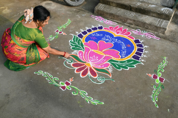 Một người phụ nữ phủ bột màu lên một hình vẽ “rangoli” để chào đón năm mới phía trước một ngôi nhà ở Hyderabad, Ấn Độ, hôm 01/01/2024. (Ảnh: Noah Seelam/AFP)