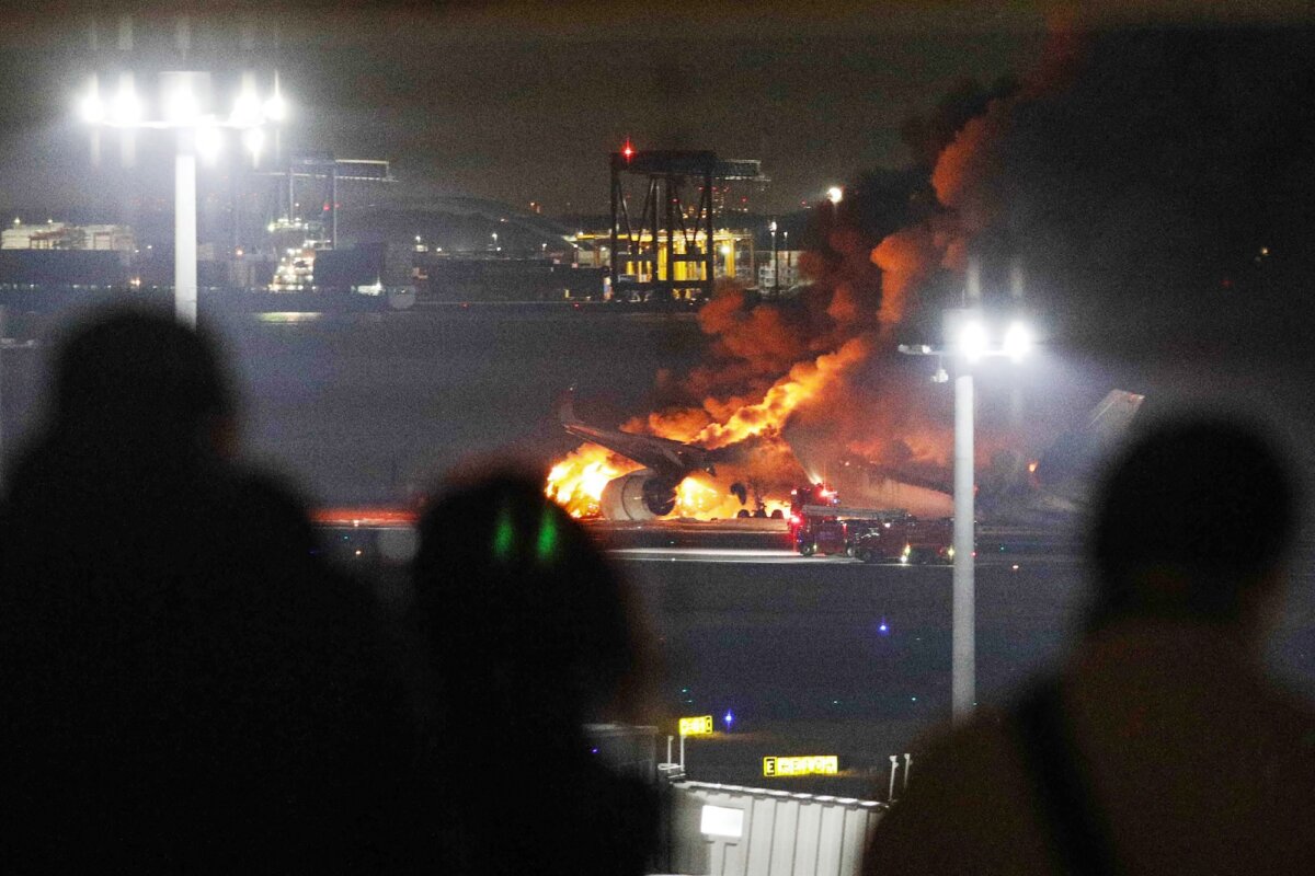 Người dân trên đài quan sát nhìn chiếc phi cơ của hãng hàng không Japan Airlines bốc cháy trên đường băng của Phi trường Haneda ở Tokyo, hôm 02/01/2024. (Ảnh: Jiji Press/AFP qua Getty Images)