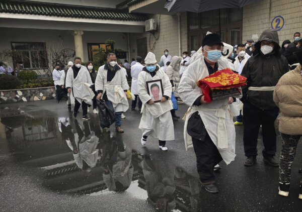 Một người đưa tang trong bộ trang phục màu trắng truyền thống bê hộp đựng tro cốt của người thân dẫn đầu một đoàn đưa tang, trong một đám tang ở Thượng Hải vào ngày 14/01/2023. (Ảnh: Kevin Frayer/Getty Images)