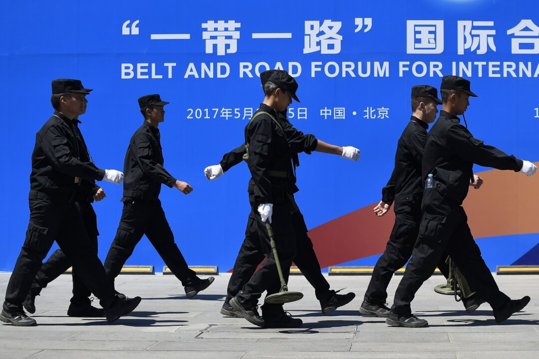 Các nhân viên bảo vệ đi ngang qua bảng quảng cáo của Diễn đàn Hợp tác Quốc tế Vành đai và Con đường tại địa điểm tổ chức diễn đàn ở Bắc Kinh ngày 13/05/2017. (Ảnh: Wang Zhao/AFP qua Getty Images)