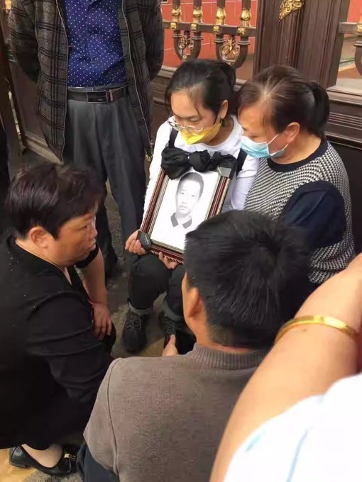 Các bậc cha mẹ giơ di ảnh của người thân đã khuất của họ, một cựu học sinh, trước Trường Dạy nghề Trung Sơn ở tỉnh Hồ Nam, Trung Quốc hồi tháng 05/2023. (Ảnh: Đăng dưới sự cho phép của anh Lý Trúc)