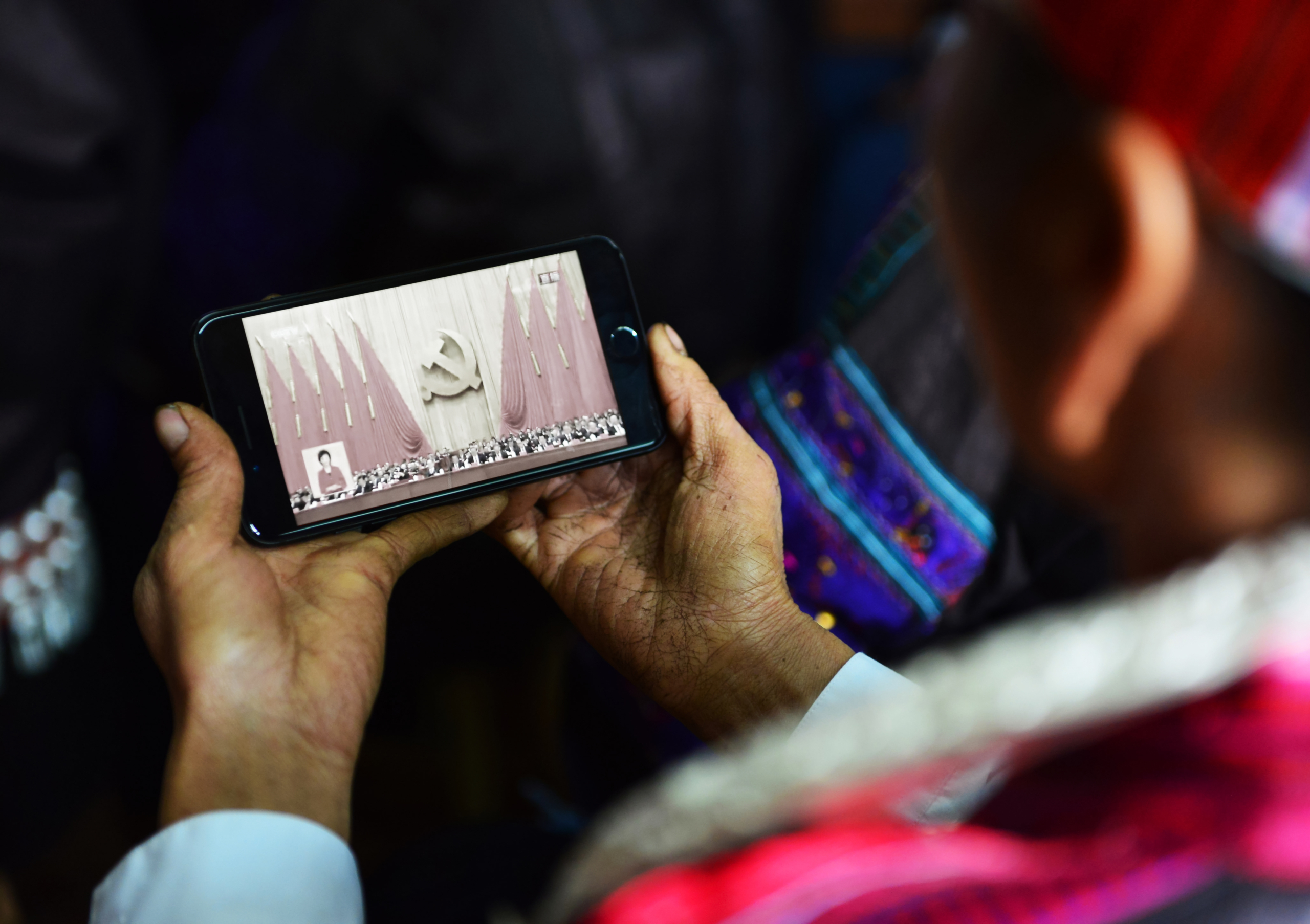 Một phụ nữ dân tộc Miêu theo dõi phiên khai mạc Đại hội Đảng lần thứ 19 trên điện thoại thông minh ở Kiến Hợi, tỉnh Quý Châu, Trung Quốc, vào ngày 18/10/2017. (Ảnh: STR/AFP qua Getty Images)