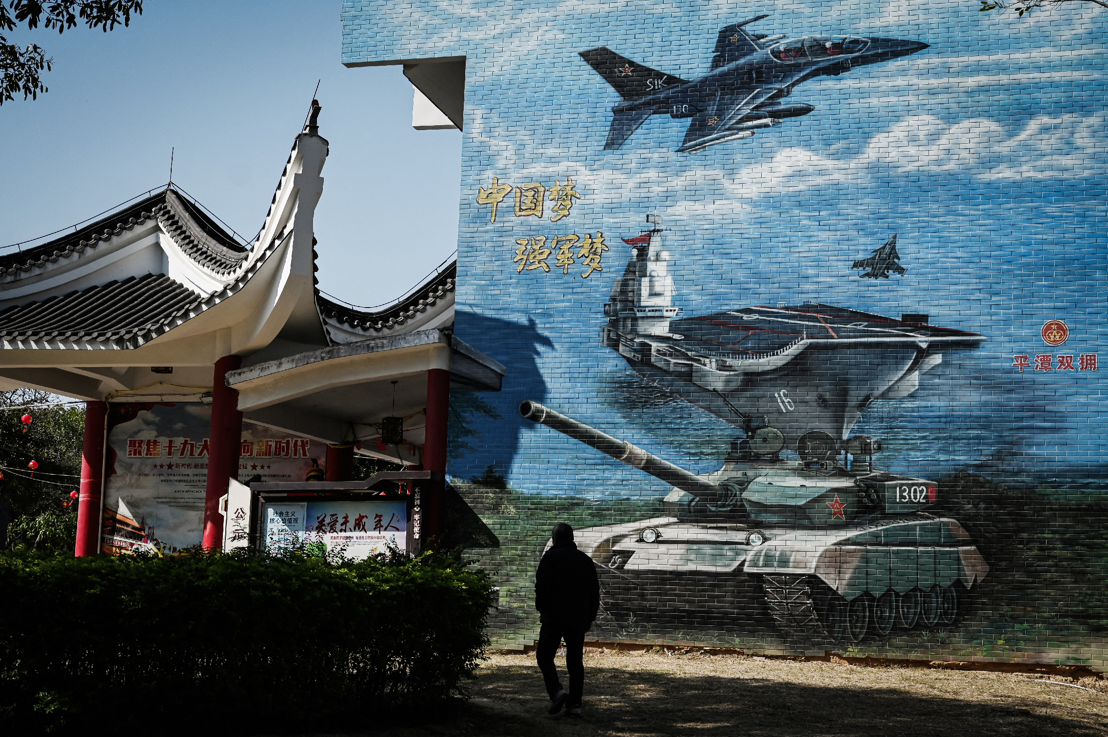 Một người đàn ông đi ngang qua bức tranh tường có chủ đề quân sự tại công viên công cộng trên đảo Bình Đàm, khu vực Trung Quốc gần nhất với đảo Đài Loan, ở tỉnh Phúc Kiến, Trung Quốc, vào hôm 14/01/2024. (Ảnh: Greg Baaker/AFP qua Getty Images)