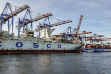 Tàu container ‘COSCO Pride’ (trái) và tàu ‘Tân Liên Vân Cảng’ (Xin Lian Yun Gang) của Tập đoàn Vận tải COSCO Trung Quốc dỡ hàng tại Cảng container Tollerort thuộc sở hữu của Công ty Cảng và Tiếp vận Hamburg (HHLA), tại cảng Hamburg, Đức, hôm 26/10/2022. Chính phủ liên minh Đức hôm 26/10/2023 đã cho phép một công ty Trung Quốc mua số cổ phần đã được giảm hạn mức xuống đối với một bến cảng ở Hamburg, sau khi Thủ tướng Scholz phản đối lại lời kêu gọi cấm hoàn toàn thương vụ mua bán gây tranh cãi này vì lo ngại an ninh. Theo thỏa thuận do nội các của ông Scholz đồng ý, hãng vận tải quốc doanh COSCO của Trung Quốc được tiến hành mua cổ phần “dưới 25%” tại khu cảng container Tollerort thuộc sở hữu của HHLA. Ban đầu COSCO đã tìm kiếm 35% cổ phần. Ông Scholz, cựu thị trưởng Hamburg, đã ủng hộ thỏa thuận của COSCO và nhiều lần nhấn mạnh tầm quan trọng của mối quan hệ thương mại bền chặt giữa Trung Quốc và nền kinh tế lớn nhất châu  u này. (Ảnh: Axel Heimken/AFP qua Getty Images)