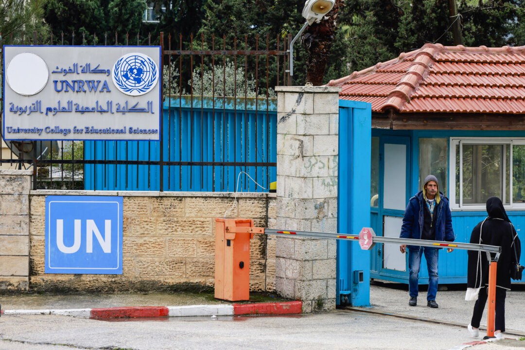 Người Palestine đứng trước lối vào của Trường Cao đẳng Khoa học Giáo dục thuộc Đại học UNRWA, thành phố Ramallah ở khu vực Tây Ngạn bị chiếm đóng hôm 29/01/2024. Tổng thư ký Liên Hiệp Quốc Antonio Guterres đã kêu gọi tiếp tục viện trợ cho UNRWA, cơ quan cứu trợ người tị nạn Palestine của Liên Hiệp Quốc, vốn đang bị đe dọa bởi một cuộc tranh cãi gay gắt sau khi nhân viên của cơ quan này bị cáo buộc tham gia vào cuộc tấn công ngày 07/10 của Hamas châm ngòi cho chiến tranh. (Ảnh của JAAFAR ASHTIYEH/AFP qua Getty Images)