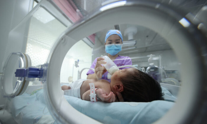 Một nhân viên y tế cho em bé bú sữa tại bệnh viện ở Đan Trại, tỉnh Quý Châu phía tây nam Trung Quốc, vào ngày 11/05/2021. (Ảnh: STR/AFP qua Getty Images)