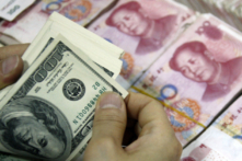 Tiền USD đang được đếm bên cạnh các tập tiền giấy 100 nhân dân tệ (RMB) tại một ngân hàng ở Hoài Bắc, tỉnh An Huy, miền đông Trung Quốc, ngày 24/09/2013. (Ảnh: STR/AFP qua Getty Images)