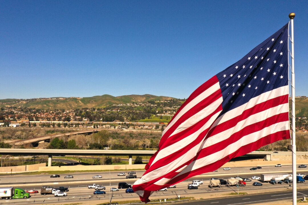 Xe hơi và xe tải chạy ngang qua một lá cờ Hoa Kỳ trên Xa lộ 91 ở Anaheim Hills, California, hôm 08/02/2023. (Ảnh: Patrick T. Fallon/AFP qua Getty Images)